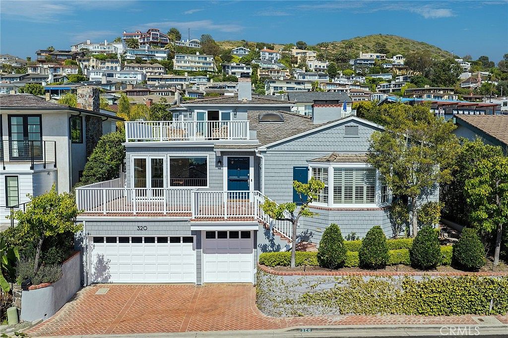 Daytime exterior of 320 Emerald Bay showing white shingles and ocean hill backdrop
