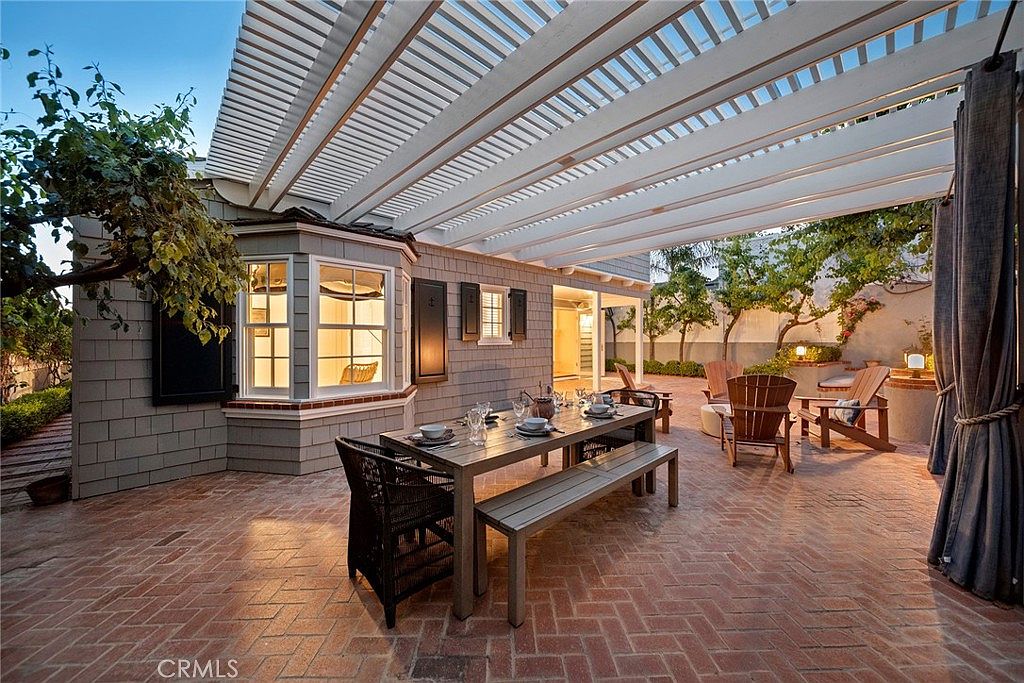 Brick patio with pergola, fireplace, and outdoor dining at twilight