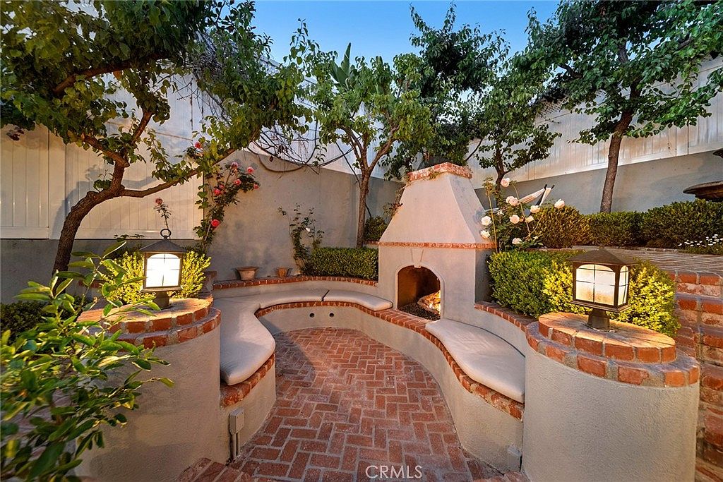 Brick courtyard fireplace with rose plantings and curved seat wall