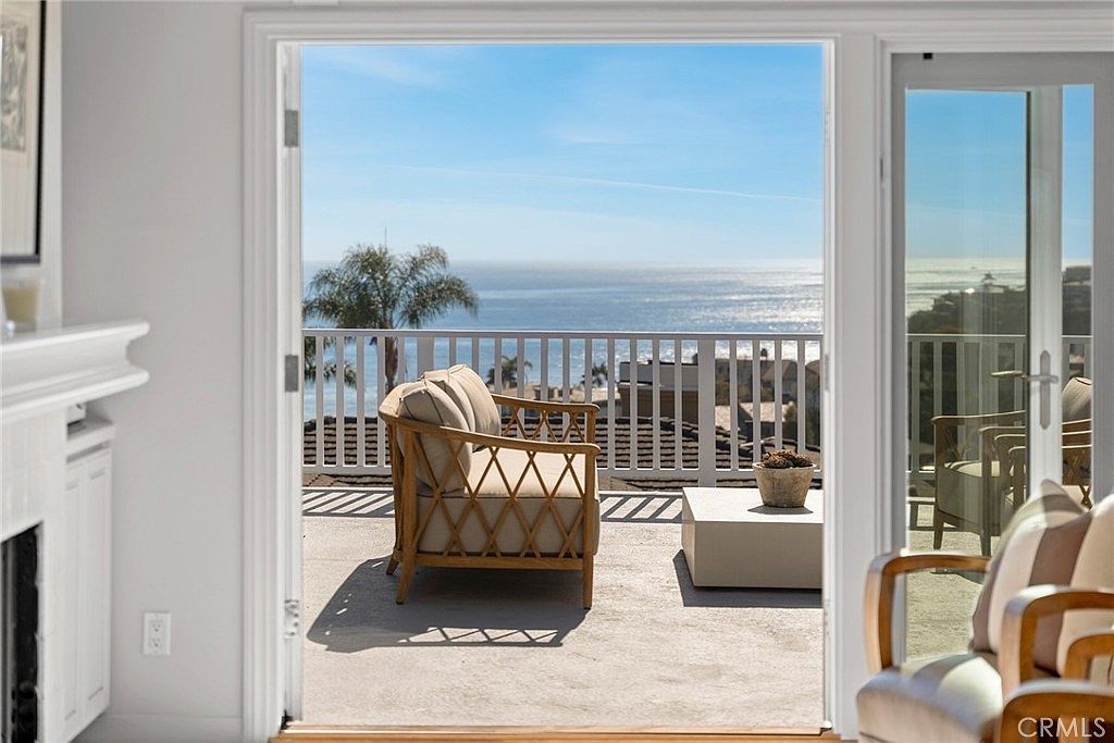 Pacific Ocean view through french doors with wicker chair on the deck